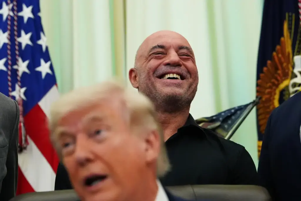 Joe Rogan laughs as President Donald Trump speaks in the Oval Office of the White House on April 18, 2026.