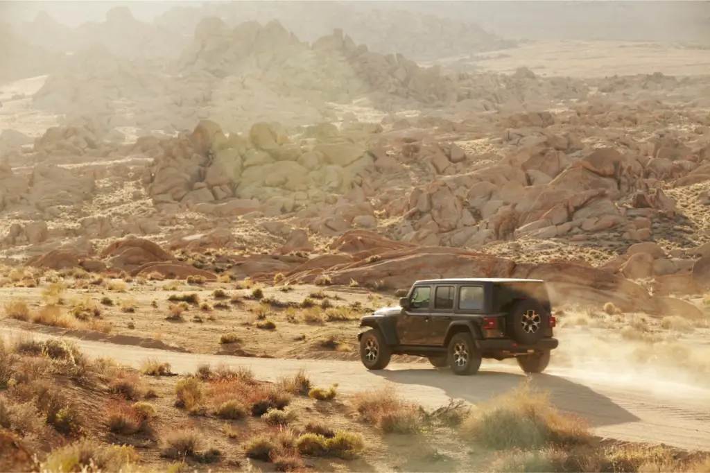 Off road car driving on a dirt road in desert landscape, Alabama hills, California.
