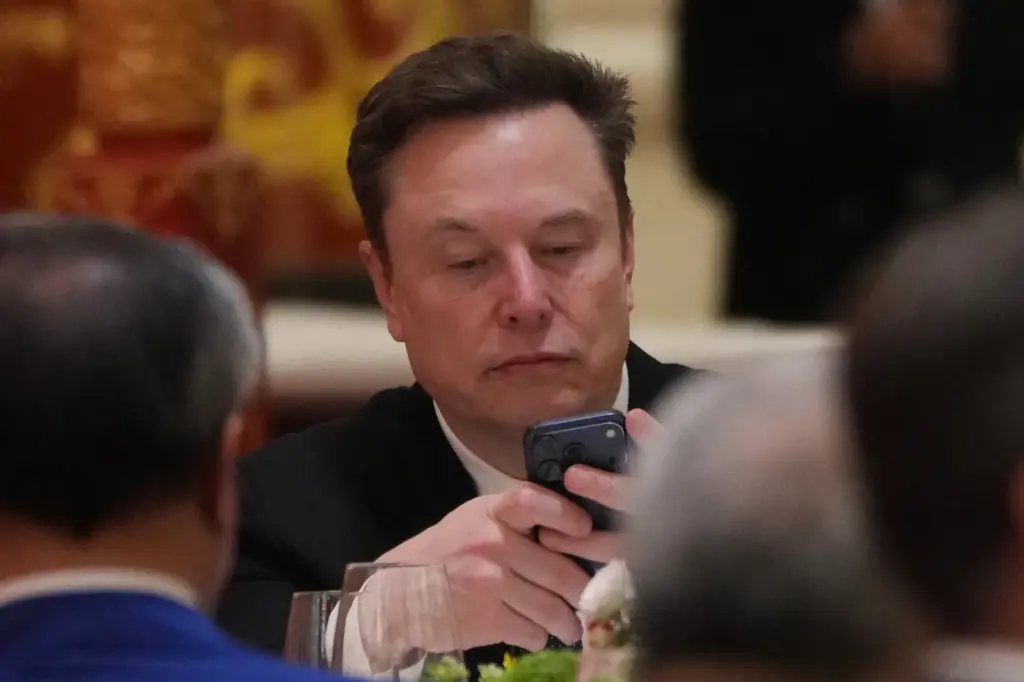 Elon Musk uses his phone during a state dinner for President Donald Trump and Chinese President Xi Jinping at the Great Hall of the People on Thursday May 14, 2026, in Beijing. (AP Photo/Mark Schiefelbein)