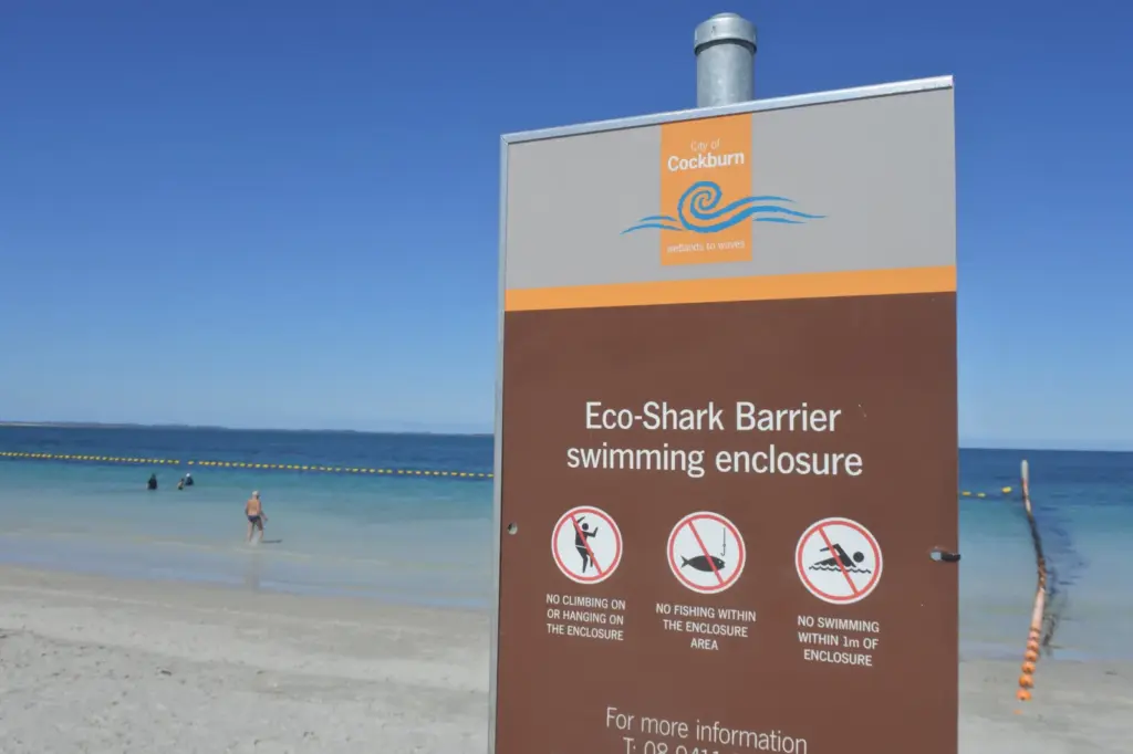 Visitors swim behind an Eco Shark Barrier sign on a beach in Fremantle, Western Australia, on November 27, 2019: