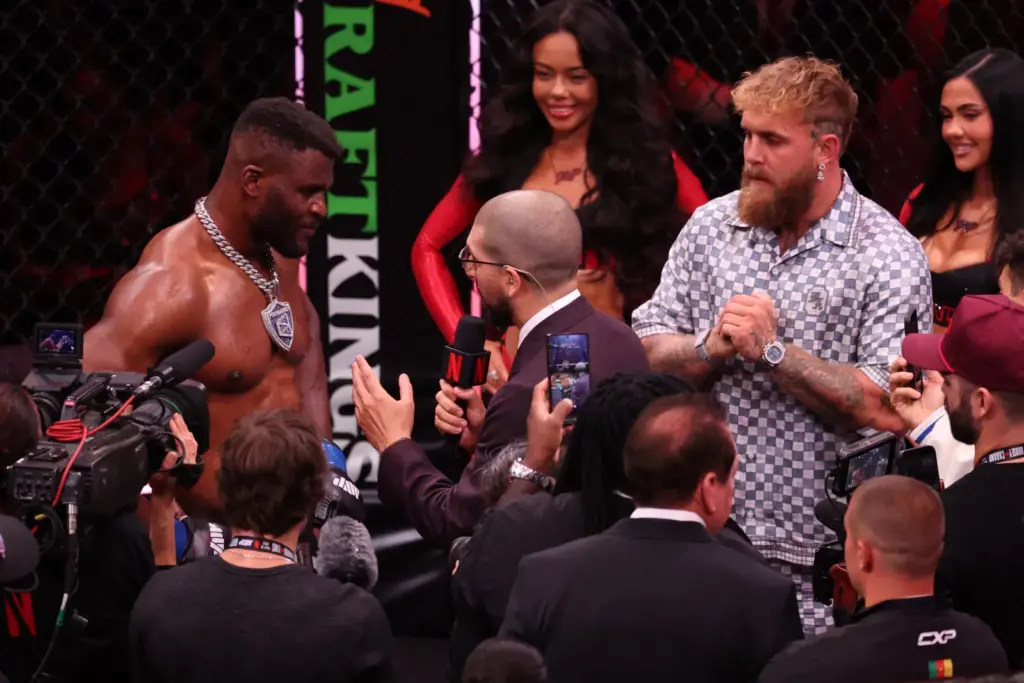 US boxer and influencer Jake Paul (R) looks on as Cameroonian-French mixed martial arts fighter Francis Ngannou (L) is interviewed after knocking out Brazilian mixed martial arts fighter Philipe Lins during their heavyweight bout at MVP MMA 1 at the Intuit Dome in Inglewood, California, on May 16, 2026. (Photo by Patrick T. Fallon / AFP via Getty Images)