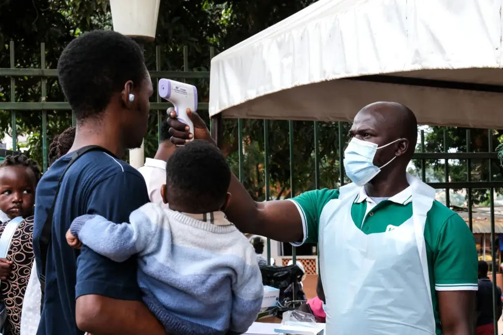 A health official uses a thermometer to screen people in front of Kibuli Muslim Hospital in Kampala, Uganda, on May 16. (AP Photo/ Hajarah Nalwadda)
